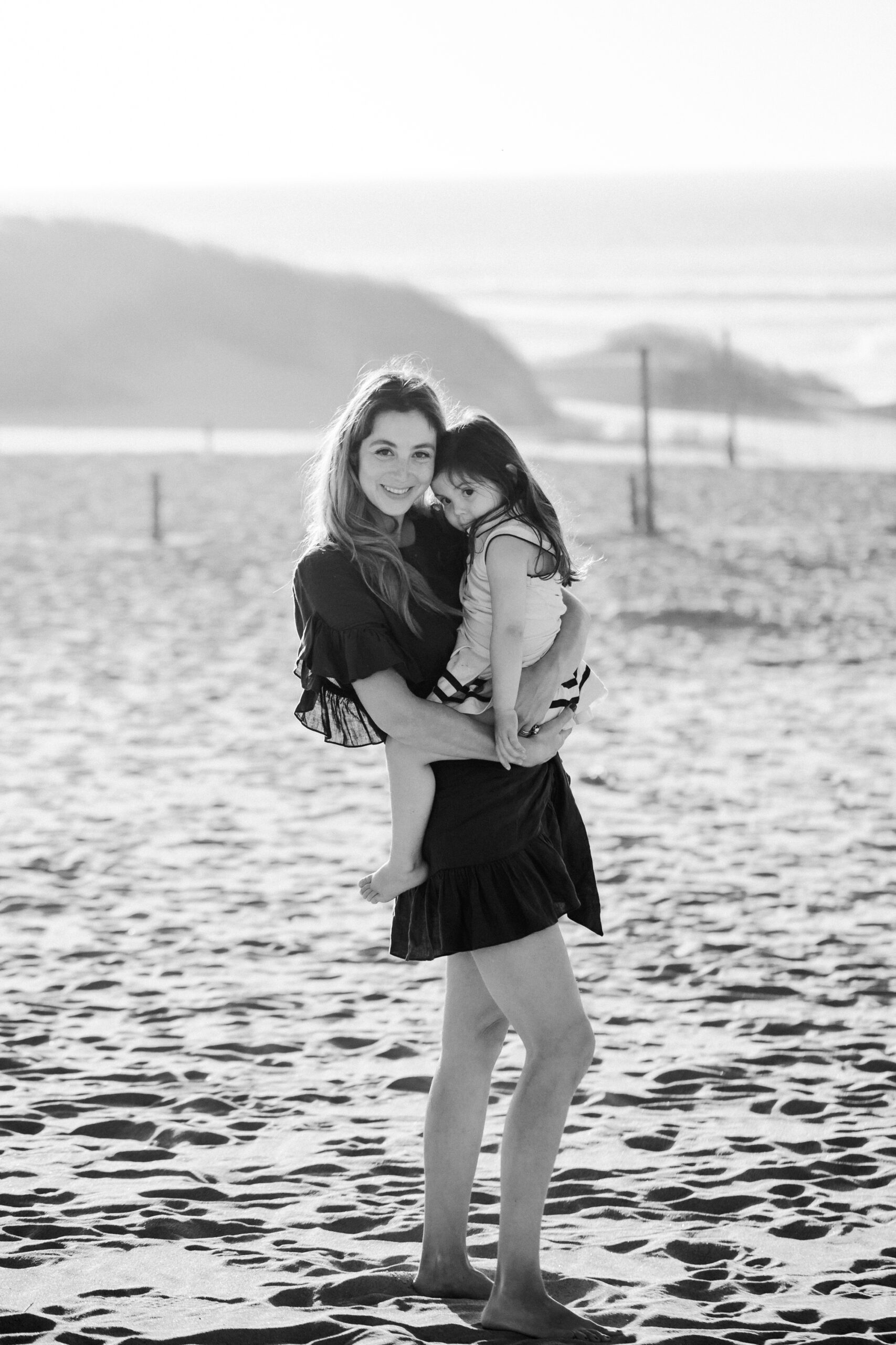 mother holding young daughter black and white image on beach